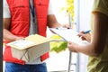 Woman signing for delivered parcels on doorstep. Courier service Royalty Free Stock Photo
