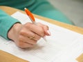 Female hand holding pen and paper on table. Royalty Free Stock Photo