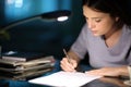 Woman signing form in the night at home