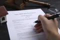 Woman signing last will and testament at black table, closeup Royalty Free Stock Photo