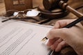Woman signing last will and testament at wooden table, closeup Royalty Free Stock Photo