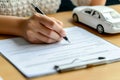 Woman signing lease paper or car insurance document. Female buying or selling new or used car. Writing signature on Royalty Free Stock Photo