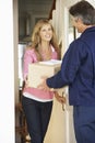 Woman Signing For Package Delivered By Courier