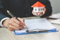 A woman signs a contract to purchase a home with a real estate agent. House model and keys in the hands of business people Royalty Free Stock Photo