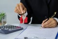 A woman signs a contract to purchase a home with a real estate agent. House model and keys in the hands of business people Royalty Free Stock Photo