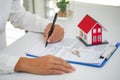 A woman signs a contract to purchase a home with a real estate agent. Model house with keys on table Royalty Free Stock Photo