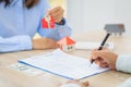 A woman signs a contract to purchase a home with a real estate agent. Model house with keys on table Royalty Free Stock Photo