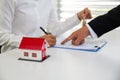 A woman signs a contract to purchase a home with a real estate agent. Model house with keys on table Royalty Free Stock Photo