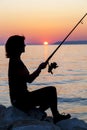 Woman silhouette fishing on rock Royalty Free Stock Photo