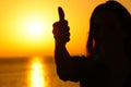 Woman silhouette gesturing thumb up at sunset
