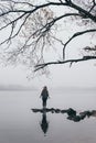 Woman silhouette on the river bank in the morning fog