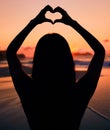 Woman, silhouette and sunset by sea with heart hands for love, care and kindness with sign, summer and dusk. Girl Royalty Free Stock Photo