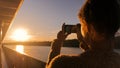 Woman silhouette taking photo of sunset with smartphone Royalty Free Stock Photo