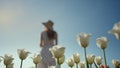 Woman silhouette wearing hat in flower garden. Unrecognizable girl on vacation.