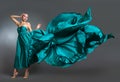 Woman in silk dress waving on wind. Flying and fluttering gown cloth over gray background Royalty Free Stock Photo