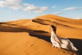 Woman in silk wedding dress with fantastic view of Sahara desert sand dunes Royalty Free Stock Photo