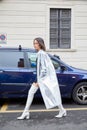 Woman with silver transparent raincoat and white boots walking before Boss fashion show, Milan