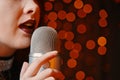 Woman singer with disco mic on bokeh light background. Royalty Free Stock Photo