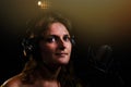 Woman singer looking at the camera at the recording Studio, black background. Portrait of a girl in large headphones with a Royalty Free Stock Photo