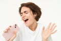 Woman singing along, listening music in wireless headphones, holding smartphone in hand, standing over white background Royalty Free Stock Photo