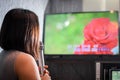 A woman singing a song at the karaoke bar holding a microphone in front of TV screen with lyrics.