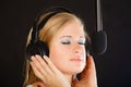 Woman singing to microphone wearing headphones in studio Royalty Free Stock Photo