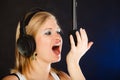 Woman singing to microphone wearing headphones in studio Royalty Free Stock Photo