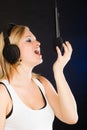 Woman singing to microphone wearing headphones in studio Royalty Free Stock Photo