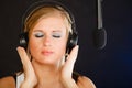 Woman singing to microphone wearing headphones in studio Royalty Free Stock Photo