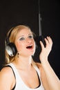 Woman singing to microphone wearing headphones in studio Royalty Free Stock Photo