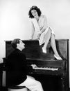 Woman singing on an upright piano with a friend playing