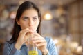 Woman sipping orange juice with straw in a restaurant Royalty Free Stock Photo