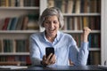 Woman sit at desk staring at cellphone celebrate great news Royalty Free Stock Photo