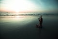 Woman sit at the seaside and meditating in yoga pose during amazing sunset. Royalty Free Stock Photo