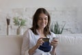 Woman sit on sofa make payment use card and smartphone