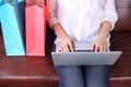 Woman sit on sofa with shooping bag beside and using laptop Royalty Free Stock Photo