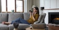 Woman sit on sofa talks to friend on speakerphone