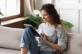 Woman sitting on sofa using tablet device buying on internet Royalty Free Stock Photo