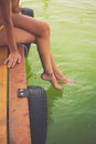 Woman sit on wooden dock cooling feet in clear water Royalty Free Stock Photo