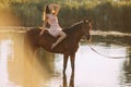 Woman sits astride a horse at river