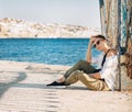 Woman sits beach sea clothes sun shadow