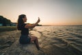 Woman sits on a beach and takes picture of the seaside Royalty Free Stock Photo