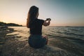 Woman sits on a beach and takes picture of the seaside Royalty Free Stock Photo