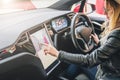 Woman sits behind wheel in car and uses electronic dashboard. Girl traveler looking for way through navigation system. Royalty Free Stock Photo