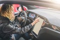 Woman sits behind wheel in car and uses electronic dashboard. Girl traveler looking for way through navigation system. Royalty Free Stock Photo