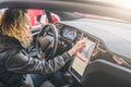 Woman sits behind wheel in car and uses electronic dashboard. Girl traveler looking for way through navigation system. Royalty Free Stock Photo