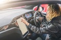 Woman sits behind wheel in car and uses electronic dashboard. Girl traveler looking for way through navigation system. Royalty Free Stock Photo