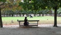 Woman sits on bench in Tuileries, Paris, on a sunny day