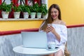 Woman sits in a brasserie and works on laptop and smartphone