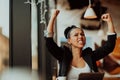 a woman sits in a cafe with her arms raised and celebrating a job well done.Business concept Royalty Free Stock Photo